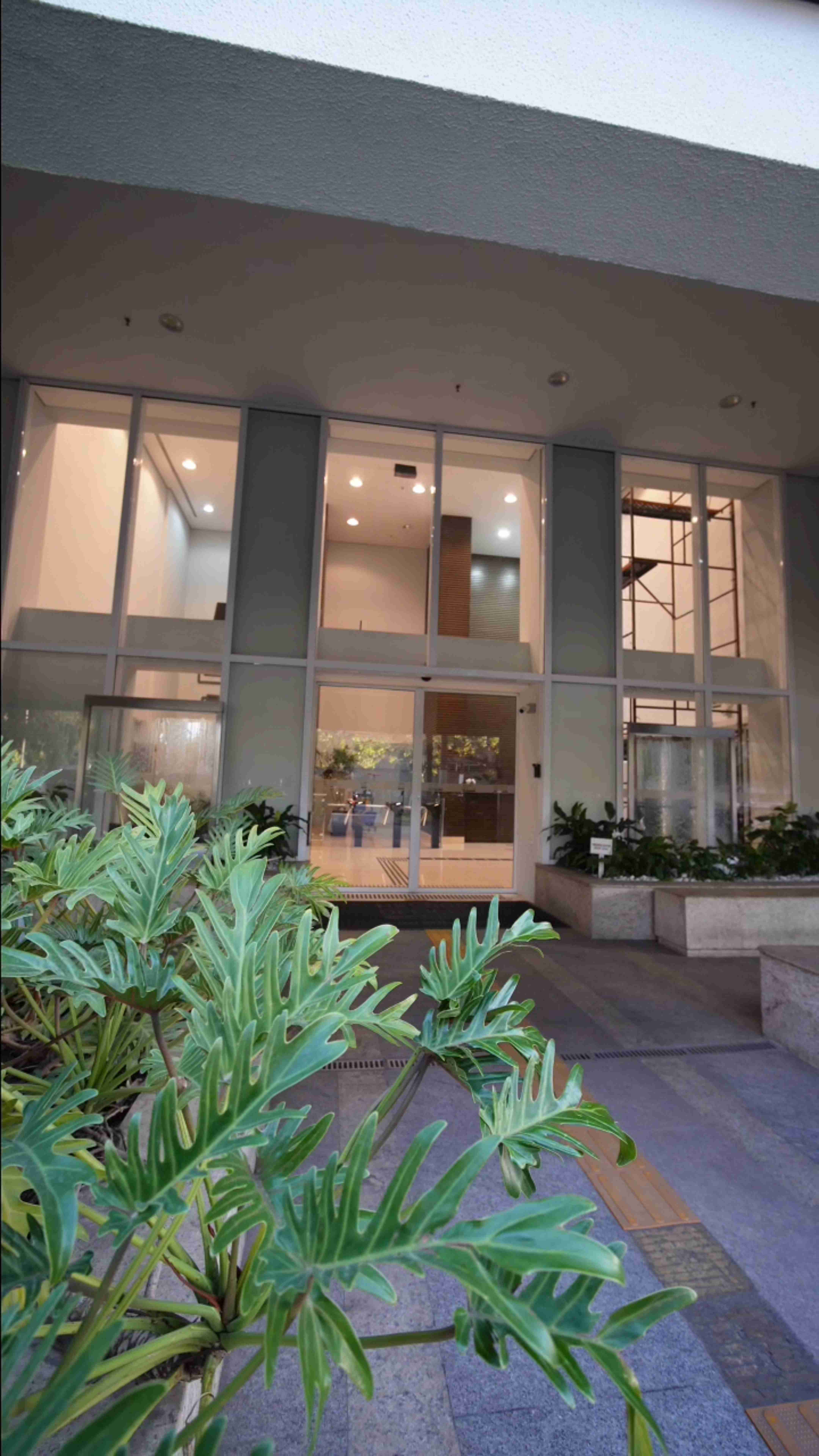 Entrada do edifício do consultório, com portas de vidro e jardim